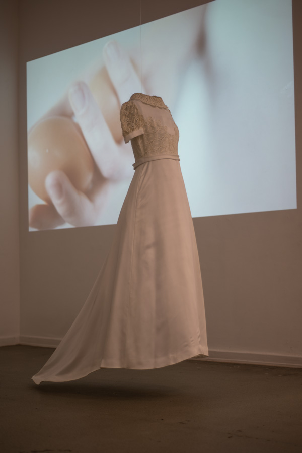 N.N. 2013. Das Brautkleid meiner Mutter. Dahinter läuft die Videoarbeit "what will be"
